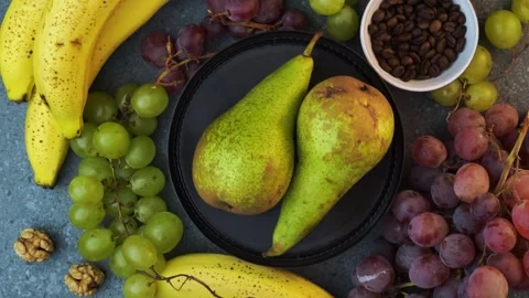 Rotating flatlay of pears with grapes bananas coffee beans and walnuts on sto Stock Footage 320029194