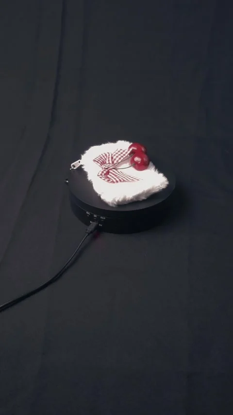 Rotating Fluffy White Pouch With Red Cherries On Black Display Stand Stock Footage 322606497