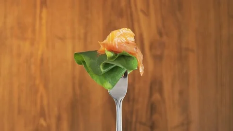 Rotating Fork With Salmon and Lettuce on Wooden Background Stock Footage 70539908