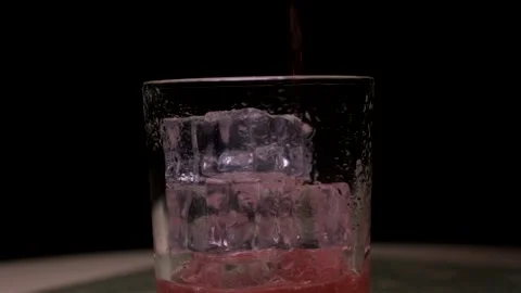 Rotating frame. The red drink is poured into a clear glass with ice. Close-up Stock Footage 152192524