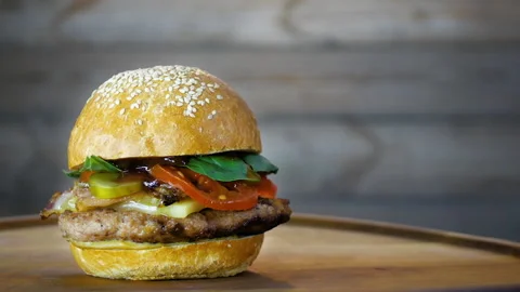 Rotating of fresh-cooked tasty burger on a wooden board, close up Stock Footage 104855508