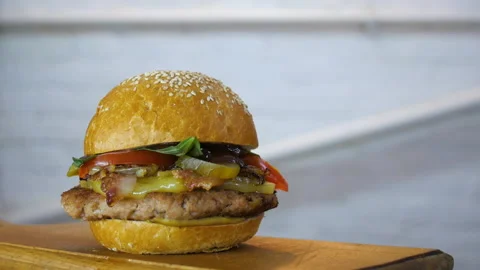 Rotating of fresh-cooked tasty burger on a wooden board, close up Stock Footage 104856155