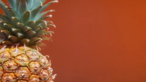 Rotating fresh pineapple on orange background Stock Footage 293625272