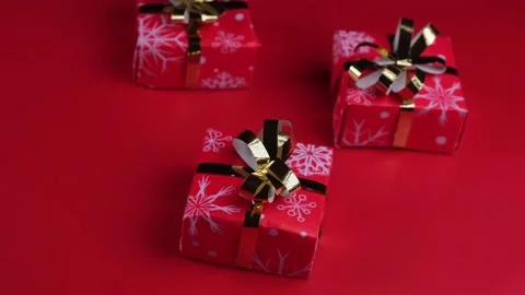 Rotating gift boxes with gold ribbon and bow on a red background. Concept for Stock Footage 167491216