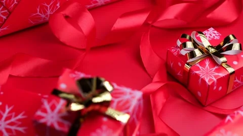 Rotating gift boxes with gold ribbon and bow on a red background. Concept for Stock Footage 167784342