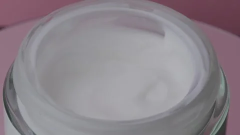 Rotating of glass jar with white face cream moisturiser on pink background. Stock Footage 242174869