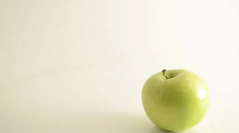Rotating Granny Smith Apple On Acrylic Against White - Crane Down Stock Footage 24469917