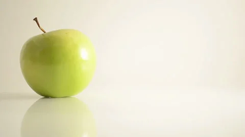 Rotating Granny Smith Apple On Acrylic Against White - Dolly Right Video stock 24470594