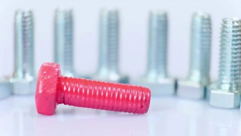Rotating group of galvanized metallic screws close-up, one of them pink colored. Stock Footage 141144958