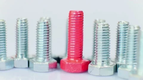 Rotating group of galvanized metallic screws close-up, one of them pink colored. Stock Footage 141145209