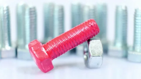Rotating group of galvanized metallic screws close-up, one of them pink colored. Stock Footage 141145623