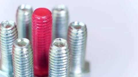 Rotating group of galvanized metallic screws close-up, one of them pink colored. Stock Footage 141146325