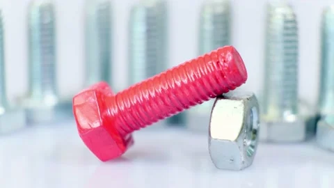Rotating group of galvanized metallic screws close-up, one of them pink colored. Stock Footage 141146804