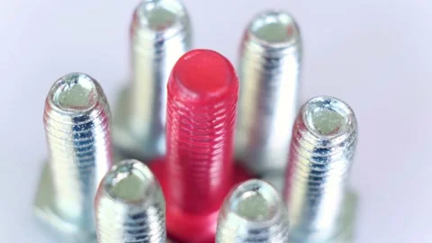 Rotating group of galvanized metallic screws close-up, one of them is pink color Stock Footage 141332156