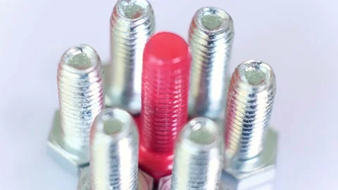 Rotating group of galvanized metallic screws close-up, one of them pink colored. Stock Footage 141500156