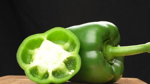 Rotating Half And Whole Green Bell Pepper On Wooden Board Black Background Stock Footage 325567124