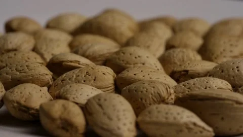 Rotating heap of whole almonds in shells white background Stock Footage 328074614