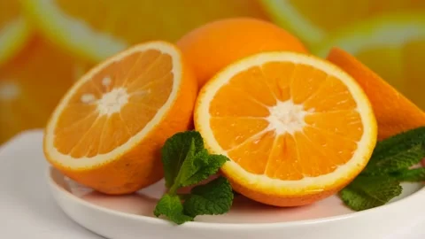Rotating juicy oranges cut in half on a white plate Stock Footage 154241802
