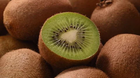 Rotating kiwi half in macro with tropical sunlight and moving summer shadows Stock Footage 330477388