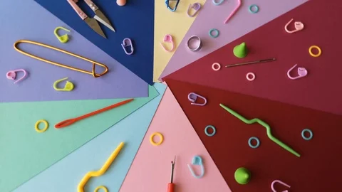 Rotating knitting tools on radially laid out colorful paper.Hobby on quarantine Stock Footage 127380895