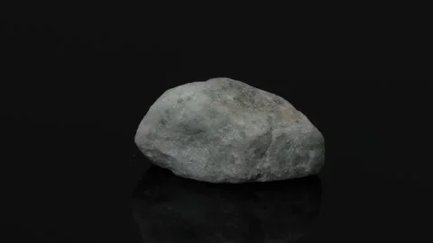 Rotating Light Gray Mineral Stone on Reflective Black Background Stock Footage 325691761