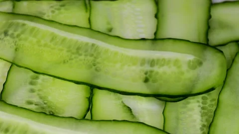 Rotating loop of fresh cucumber slices arranged in overlapping pattern Stock Footage 314363230