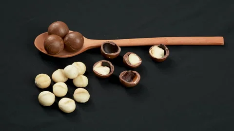 Rotating Macadamia Nuts Whole and Peeled with Wooden Spoon. Stockbeeldmateriaal 332833979