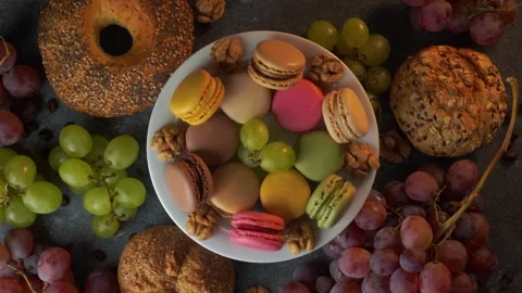 Rotating macarons with red grapes buns coffee beans and walnuts top view Stock Footage 319967384