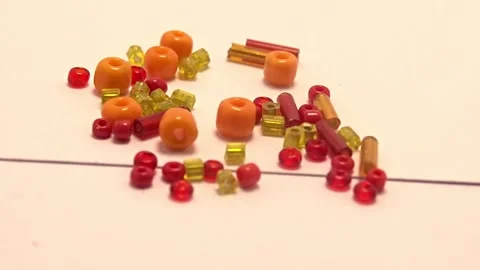 Rotating macro video of colorful craft beads on a white surface Stock Footage 337323032