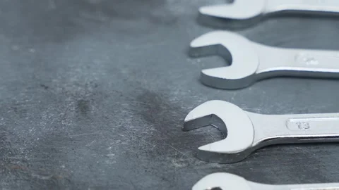 Rotating metal wrenches displayed in parallel formation on a dark surface. 스톡 동영상 328034390