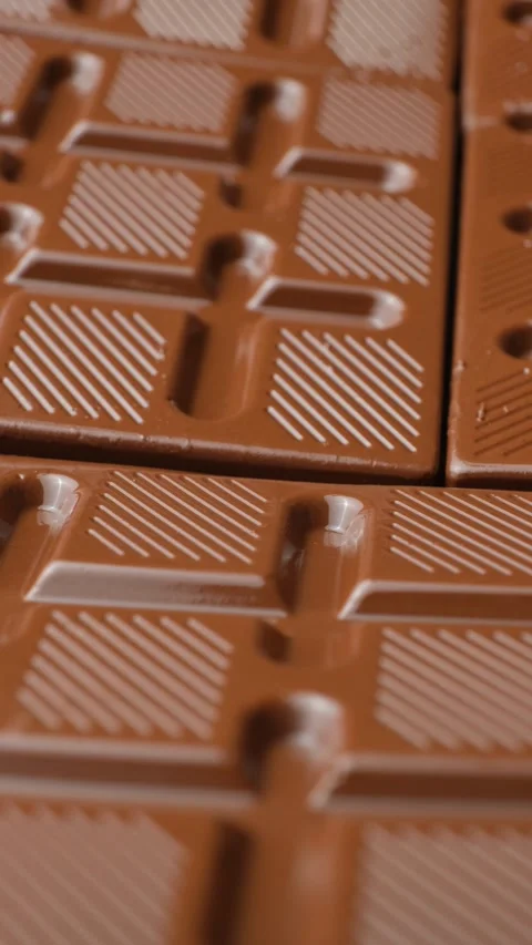 Rotating milk chocolate bar texture with striped pattern detail vertical shot. Stock Footage 345640042