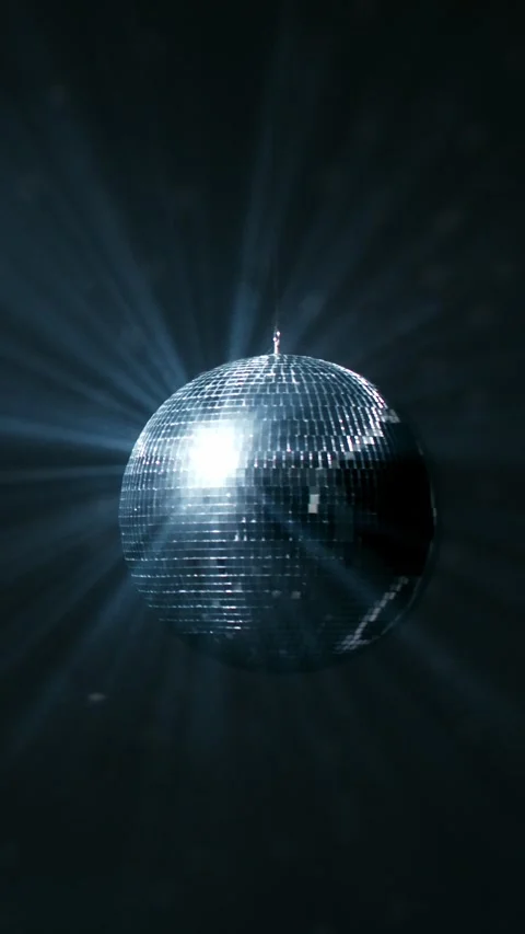 Rotating mirrored disco ball reflecting bright blue light beams in a dark Stock Footage 347734620