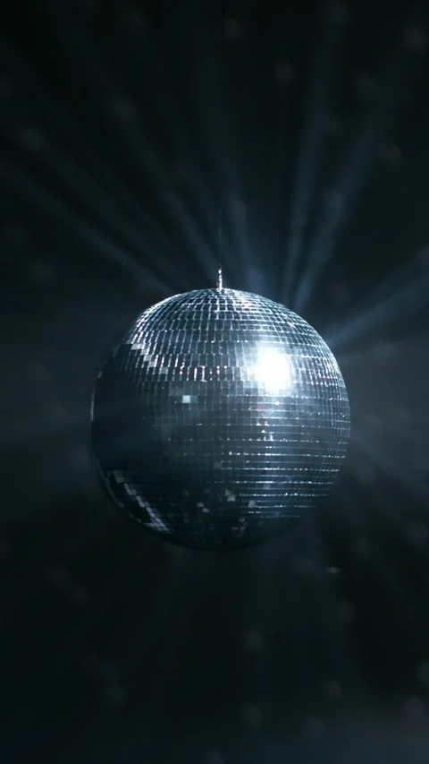 Rotating mirrored disco ball reflecting bright blue light rays in dark Stock Footage 347734749