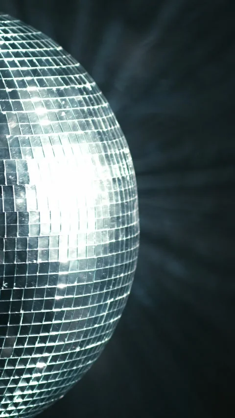 Rotating mirrored disco ball reflecting bright light and casting beams against a Stock Footage 347734975