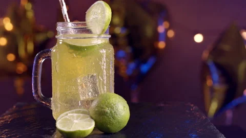 Rotating mojito cocktail with lime with party background at night Stock Footage 135560766