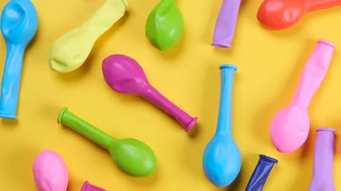Rotating multi-colored balloons on a yellow background, top view, the concept of Stock Footage 211050958
