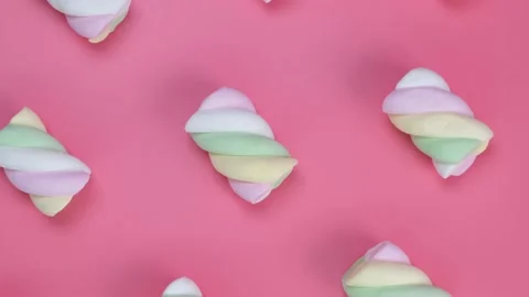 Rotating multi-colored chewy marshmallows on a pink background, the concept of a Stock Footage 198567849