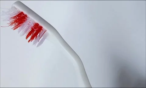 Rotating old, used, red and white striped toothbrush on white background. Stock Footage 314755517