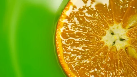 Rotating orange with green background. Beautiful light in the water Video stock 125885219