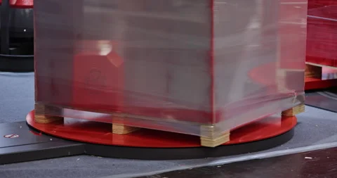 Rotating pallet platform wraps stacked cargo with clear stretch film at Video stock 346230085