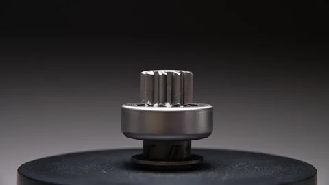 A rotating part on a gray gradient background. A starter drive is a metal part Stock Footage 328908478