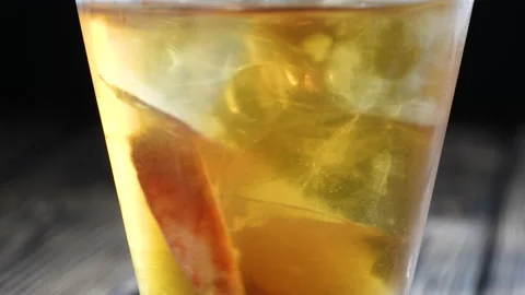 Rotating peach iced tea in the glass with fruit slices and ice cubes. Healthy Stock Footage 167941966