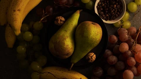Rotating pears on brown plate with grapes bananas coffee beans and walnuts Stock Footage 320566803