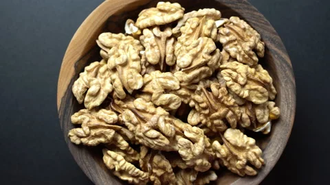 Rotating peeled raw walnuts in a wooden bowl on a wooden background. Stock Footage 229414088