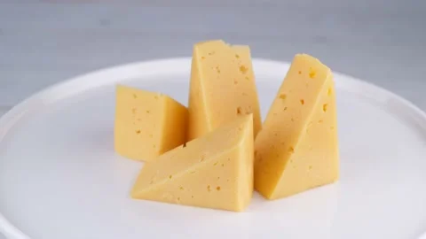 Rotating pieces of hard cheese on a white plate or background close-up Stock Footage 194648737