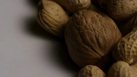 Rotating pile of mixed peanuts almonds and walnuts in shells Stock Footage 328074711