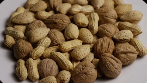 Rotating pile of mixed walnuts peanuts and almonds in shells Stock Footage 328085565