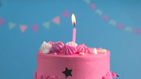 Rotating pink cake with a burning candle concept birthday parties or anniversary Stock Footage 247960838