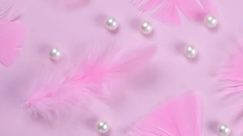 Rotating pink feathers on a pink background with pearls, a fashionable Stock Footage 211410131
