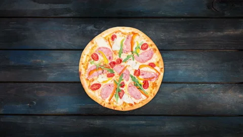 Rotating pizza with ham, sweet pepper, rucola, tomatoes and iceberg lettuce on a Stock Footage 88514935